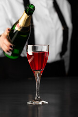 bartender makes a kir royal cocktail on a dark background