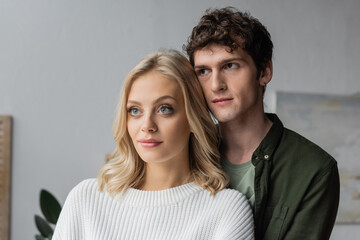 portrait of curly young man and blonde woman in white sweater.