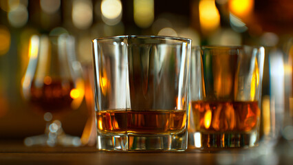 Close-up of pouring whiskey or rum on the bar, dark toned background