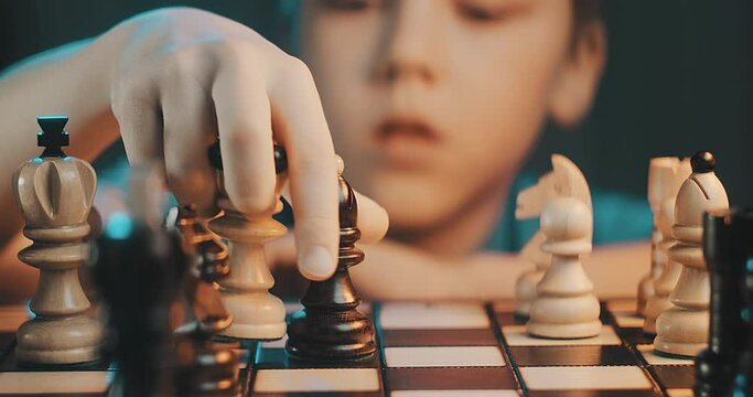 Cute little boy playing chess at home. Smart kids. Game good for brain intelligence concept. Clever concentrated and thinking child while playing chess. Kids early development. Figures on chessboard.
