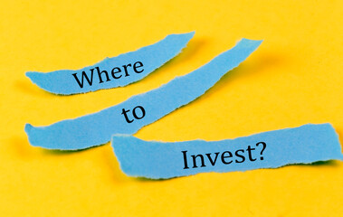 WHERE TO INVEST text on a blue pieces of paper on yellow background, business concept