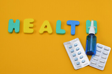 pills and the inscription health from the letters of the children's alphabet on yellow background