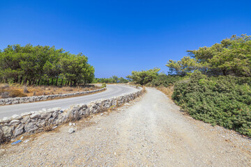 Beautiful view of asphalt road merging with blue sky on horizon. Greece. 