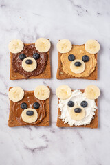 Breakfast toasts with nut butter, banana and blueberry with cute funny animal face. Kids food, breakfast for kids or school lunch. Top view