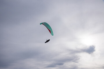 paraglider high above, grey cloudy sky