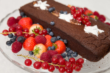 Chocolate brownie cake with fresh blueberries,  raspberries, strawberries, red currant and white stars made of powdered sugar. Homemade cake decorated with fruit. Festive concept