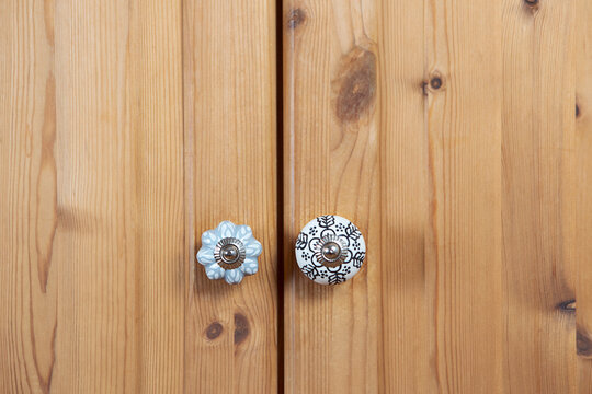Ceramic knob close-up by closed wooden wardrobe. Creative retro furniture decor background.