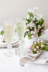 Beautiful table decor for a wedding dinner with a spring blooming apple tree flowers. Celebration of a special event. Fancy white plates, wineglasses