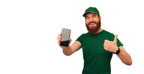 Cheerful delivery man in green shows the screen of his phone and a thumb up.
