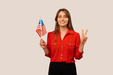 Happy young proud woman is holding USA flag and two fingers for peace.