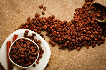 Coffee cup and coffee beans on a wooden table and sack background, Vintage color tone