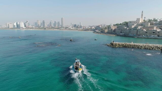 Aerial Footage of a fishing boat sailing towards the port of the beautiful old city of Jaffa, Tel Aviv.