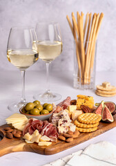 Food photography of white wine, salami, grissini, cracker, cheese, fig, parmesan, prosciutto, cheddar, olive, almond, nuts