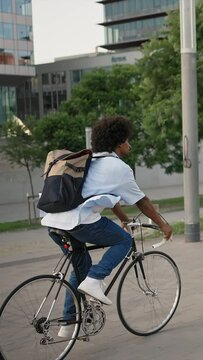 Professional African American man going to work on bicycle in city street - vertical video