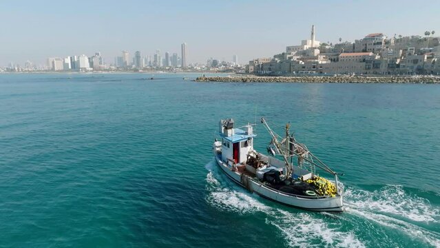 Aerial Footage of a fishing boat sailing towards the port of the beautiful old city of Jaffa, Tel Aviv.