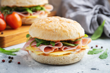 Two homemade sandwiches with ham, cheese and arugula on a concrete table. - obrazy, fototapety, plakaty