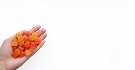 Group of red, orange and yellow multivitamin gummies in the hand isolated on white background