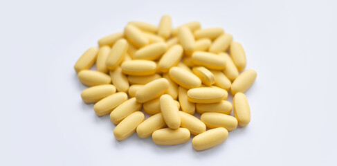 Close-up texture of yellow multivitamin tablets on white background. Healthy lifestyle concept