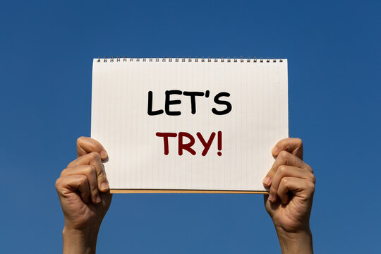 Let's try message on a notebook paper which is held by 2 hands with isolated blue sky background. This text can be used in any business concept about encouraging peopleto do anything.
