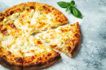 Italian pizza four cheeses with stretching cheese and basil on a light concrete background