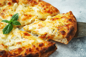 Italian pizza four cheeses with stretching cheese and basil on a light concrete background