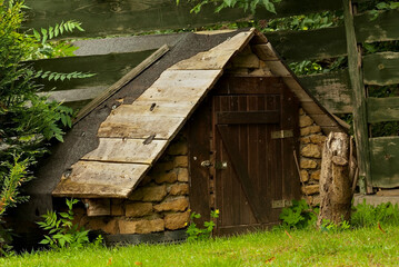 Komórka , szopa , mała chatka gospodarcza zbudowana z kamieni i drewna w pobliżu płotu na podwórku . 
