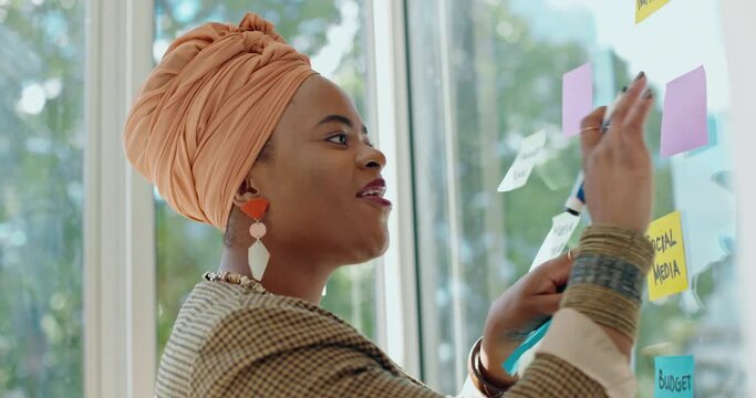 Thinking, brainstorming and ideas, black woman at moodboard with smile writing notes on glass wall. Strategy, planning on sticky note at workshop and goals in future creative startup business project