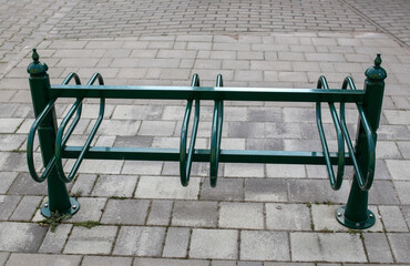 Green metal bicycle storage on the cobbled street