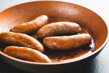 Fried bratwurst (pork sausages) on a frying pan close-up on the kitchen table, view from above, copy space