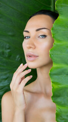 Beautiful Woman face with Natural nude make-up on a tropical leaf background. Healthy life. Purity