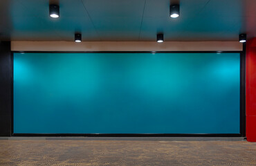 Long green glass wall for advertising space. Shopping mall glass wall at night. Lighting lamps...