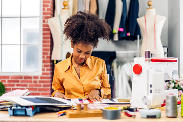 Portrait of young african american woman fashion designer stylish sitting and working with color...