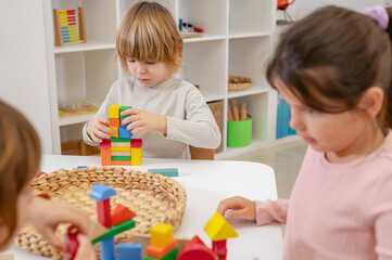 Obraz na płótnie Canvas Kindergarten children playing with colorful building blocks. Healthy learning environment. Learning through play.