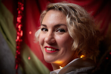 Portrait of a beautiful laughing funny blonde girl with light of garland on a dark background before Christmas or New Year