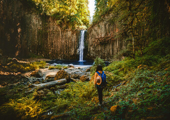 A woman standing and looking on beautiful waterfall of Abiqua Creek, Abiqua Falls. Abiqua Falls is one of the hidden gems in Oregon. Abigua falls flowing over the lava rock formation