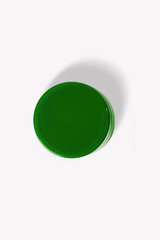 Green cosmetic jar on a light background.