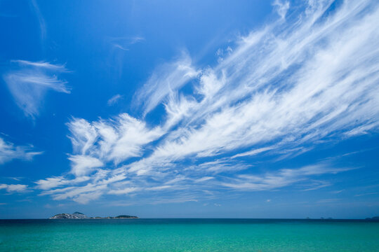 Summer in Ipanema beach with a view to the Atlantic Ocean and Cagarras Archipelago, which looks small under long clouds in a blue sky sunny day, Rio de Janeiro, Brazil
