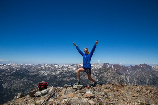 A Young Woman Celebrates Climbing To The Summit Of A Peak In The Wallowas Of Oregon Near The Town Of Joseph.