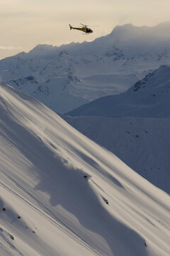 Skier making turns down a mountain with a helicopter.