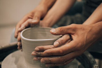 Obraz na płótnie Canvas Couple mold ceramic vase in a pottery workshop, hands close up.