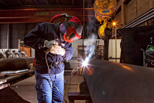 A shipyard worker welds metal panels