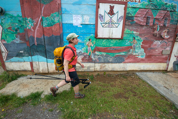 A backpacker hikes by a colorful building in the Kalinago territory on Segment 6 of the Waitukubuli National Trail on the Caribbean island of Dominica.
