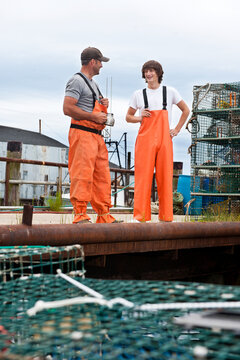 Lobsterman shares jokes with his teenage apprentice at wharf