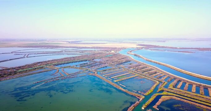 Motion over landscape with bright blue green Venetian channels among narrow ennobled strips of land on sunny day aerial view