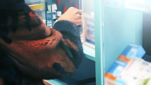 Senior woman buys medicines in a pharmacy. The pharmacist returns the prescription to the customer