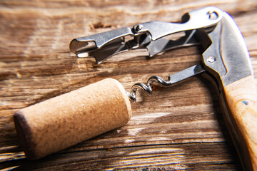 sommelier's knife with a wine cork on an old wooden table. Close-up. Selective focus. Space for text.