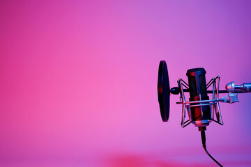 black microphone on pink and purple neon background with copy space.