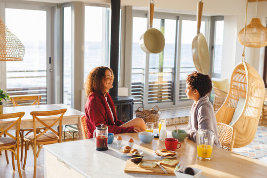 Happy diverse lesbian couple eating breakfast in kitchen