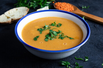 Red lentil soup puree in a bowl  on dark background. Traditional middle eastern cuisine. Vegan food.