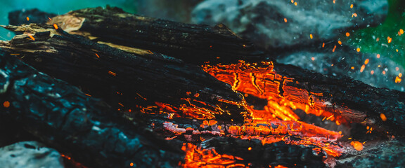 Vivid smoldered firewoods burned in fire close-up. Atmospheric warm background with orange flame of...